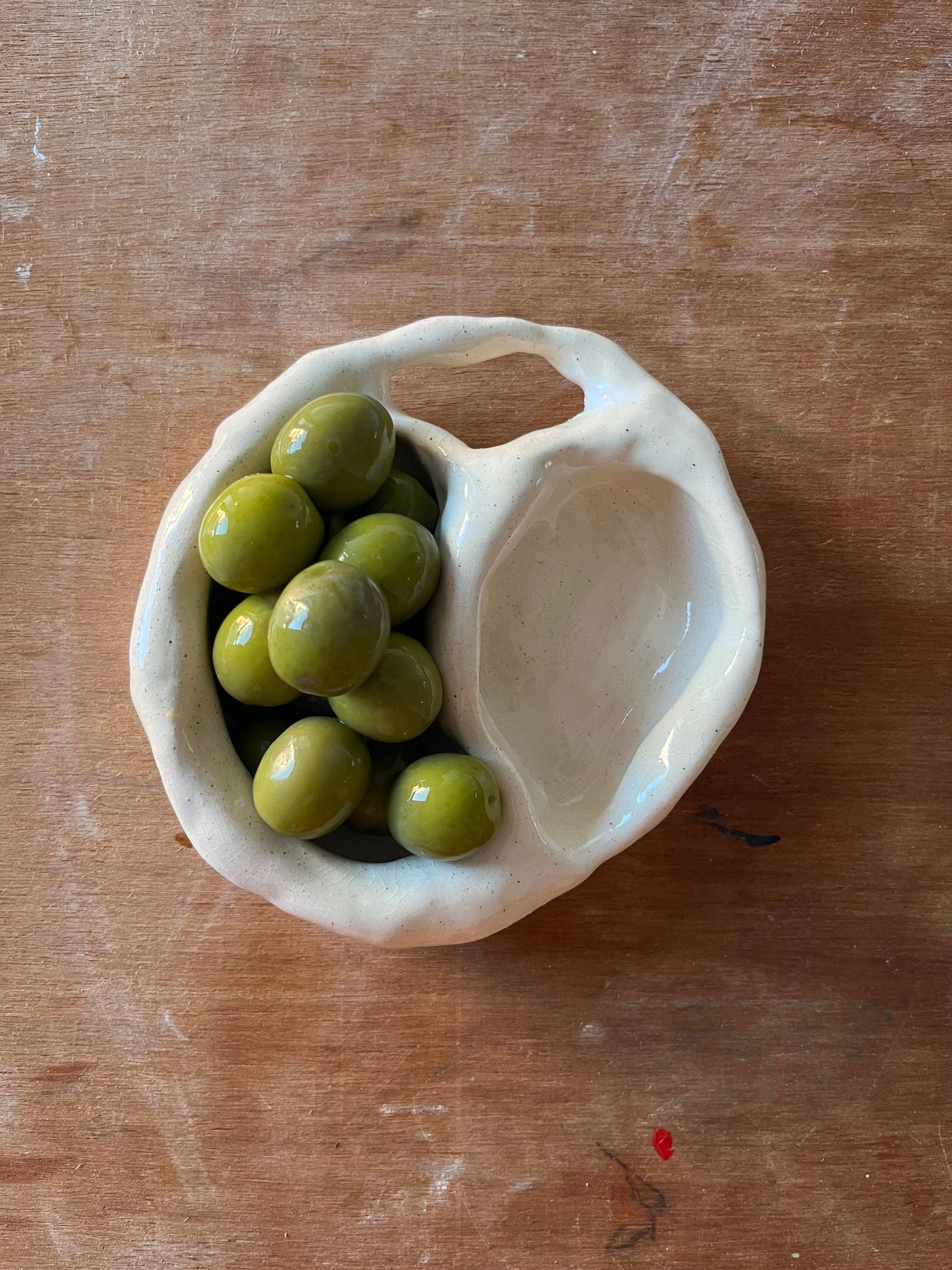 Organically-shaped, hand-built stoneware olive dish from NYC based artist, Kelsey Malone. Put your olives in one side and the pits in the other. Created using domestically sourced, non-toxic, and food safe materials. Each dish is unique and measurements will vary slightly per item. 